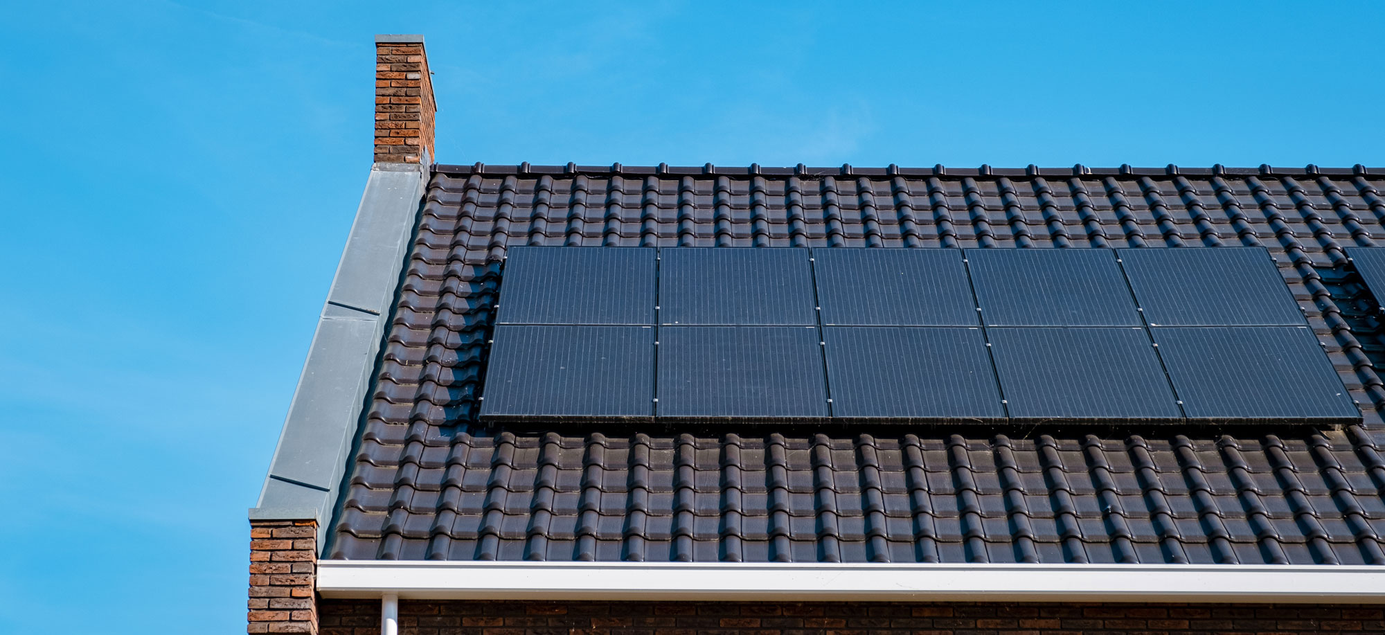 Ein Haus mit Solarpaneelen auf dem Dach, das die Nutzung erneuerbarer Energien veranschaulicht.